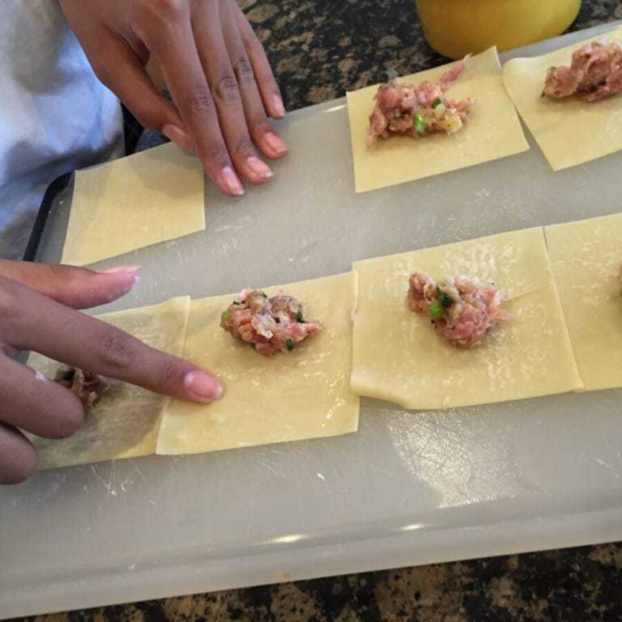 uncooked pork wonton filling being placed in wonton wrappers