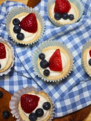 Overhead image of Red, White, and Blue Sugar Cookie Cups on a blue gingham cloth