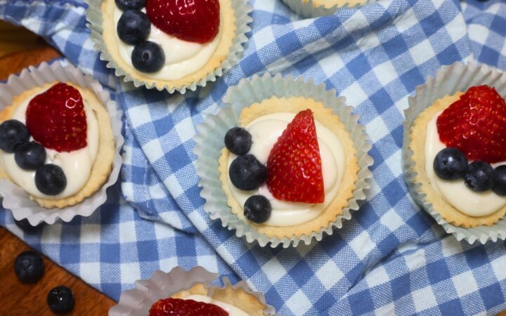 Overhead image of Red, White, and Blue Sugar Cookie Cups on a blue gingham cloth