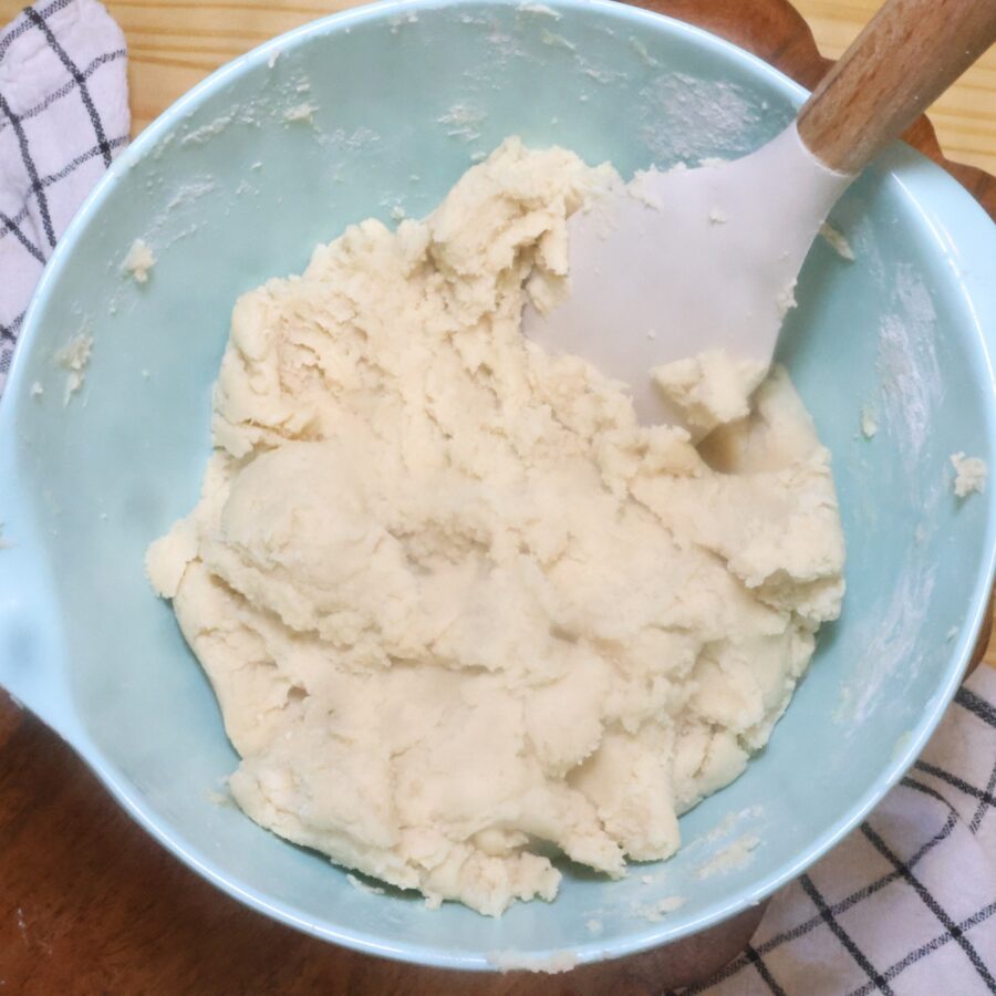 Homemade sugar cookie dough in a blue bowl with a spatula in it