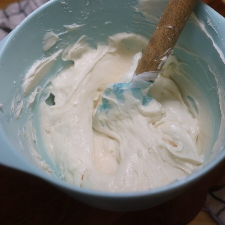 Cream Cheese filling for sugar cookie cups in a blue bowl with a spatula