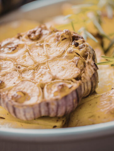 Close up image of a head of roasted garlic on a plate