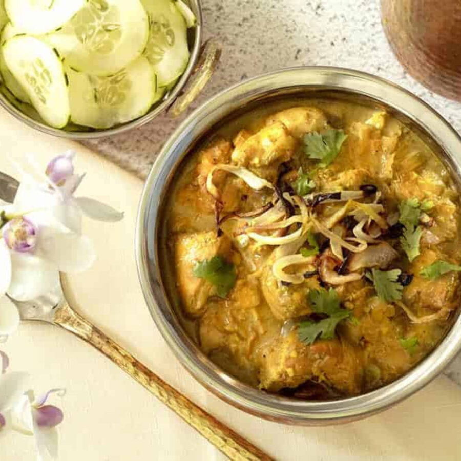 A bowl of South Indian curry with a side of sliced cucumber