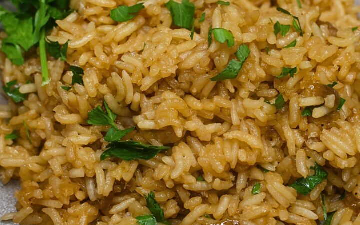 Close up image of stick of butter rice on a plate garnished with parsley