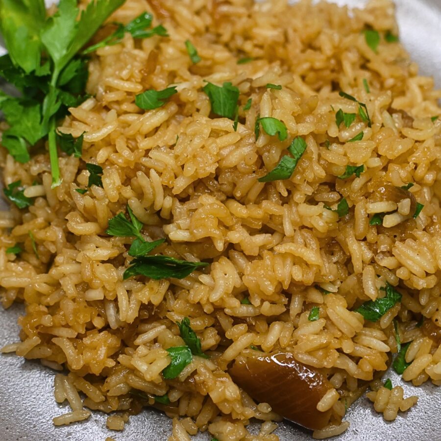 Close up image of stick of butter rice on a plate garnished with parsley