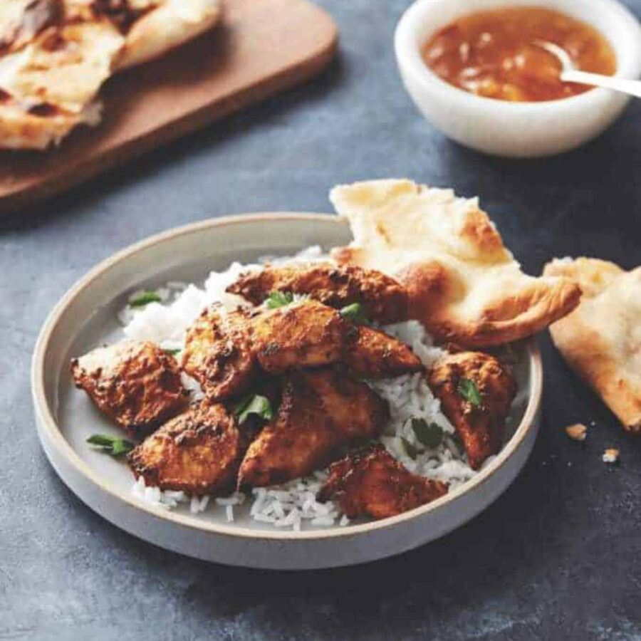 tandoori chicken on a plate with rice and naan