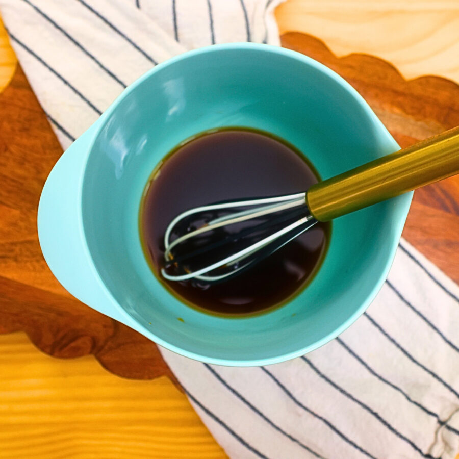 Sauce for Thai Basil Chicken in a blue bowl with a whisk