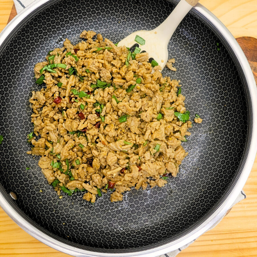 Completely assembled Thai Basil Chicken in a large skillet with a spatula