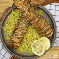 Two Tortilla Kebabs on a bed of seasoned yellow rice with lemon slices