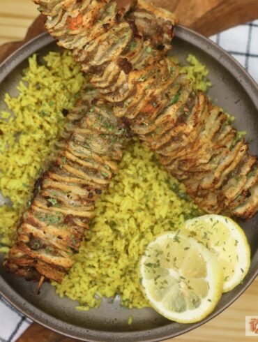 Two Tortilla Kebabs on a bed of seasoned yellow rice with lemon slices