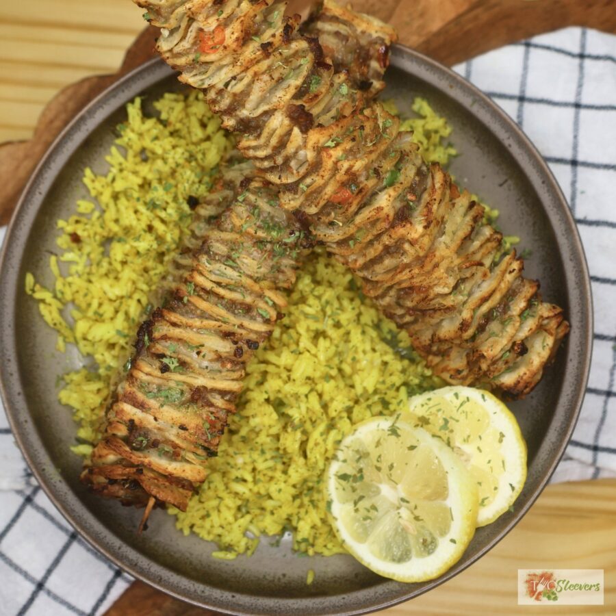 Two Tortilla Kebabs on a bed of seasoned yellow rice with lemon slices