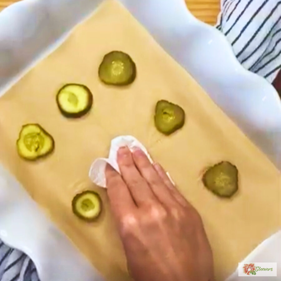 A hand drying pickle slices with a paper towel