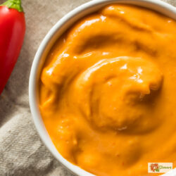 overhead image of chipotle aioli in a white bowl with a red pepper next to it