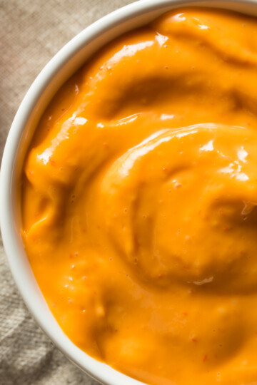 overhead image of chipotle aioli in a white bowl with a red pepper next to it