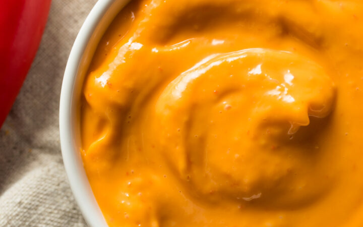 overhead image of chipotle aioli in a white bowl with a red pepper next to it