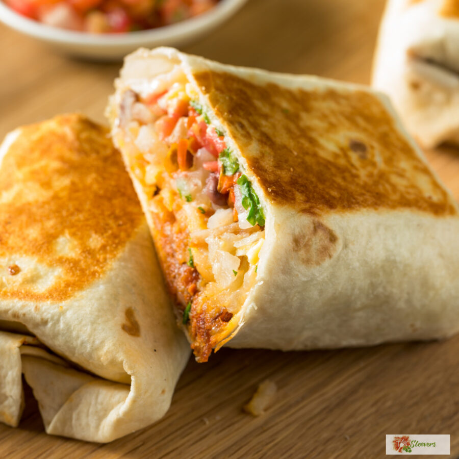 Close up image of a chorizo breakfast burrito  cut in half on a cutting board