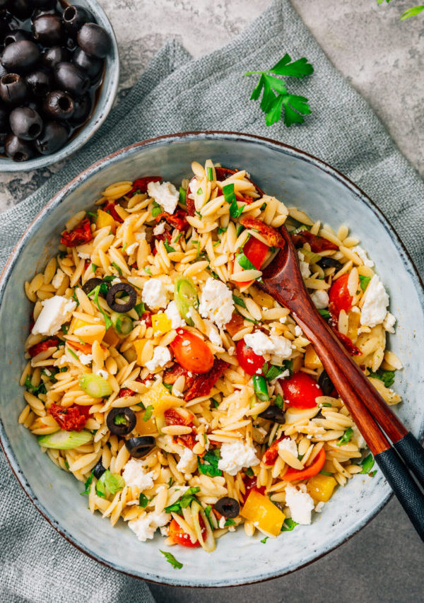 Overhead image of Orzo Salad in a bowl with serving spoons