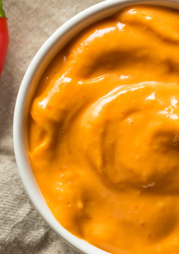 overhead image of chipotle aioli in a white bowl with a red pepper next to it