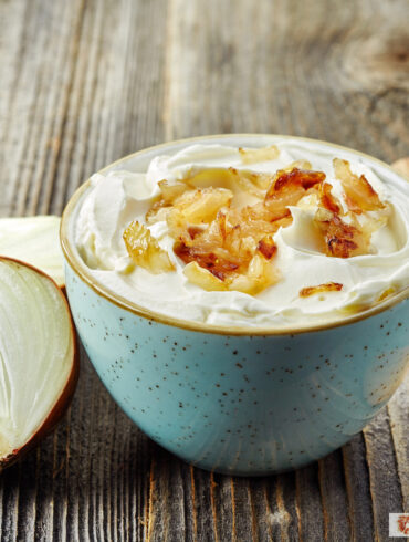 French Onion Dip in a blue bowl with an onion next to it