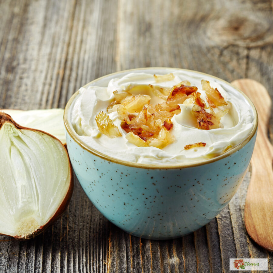 French Onion Dip in a blue bowl with an onion next to it