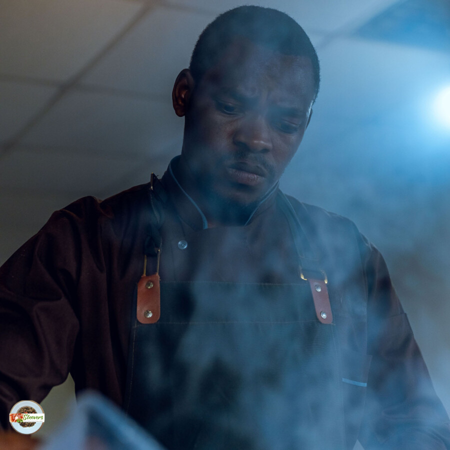 A chef in a kitchen with smoke in front of his face